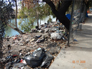 Opening in chain link fence along Smith Canal levee with debris covering the whole side of the levee - Date of 03.11.2020 shows at the bottom of the photo