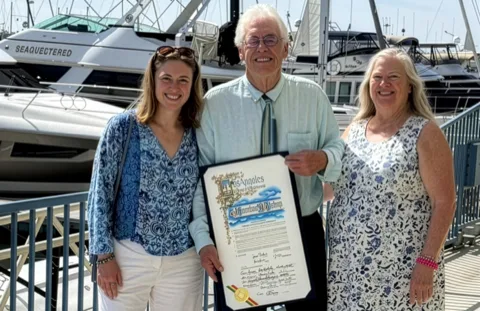 Jon Bishop holding a framed award with his wife and daughter