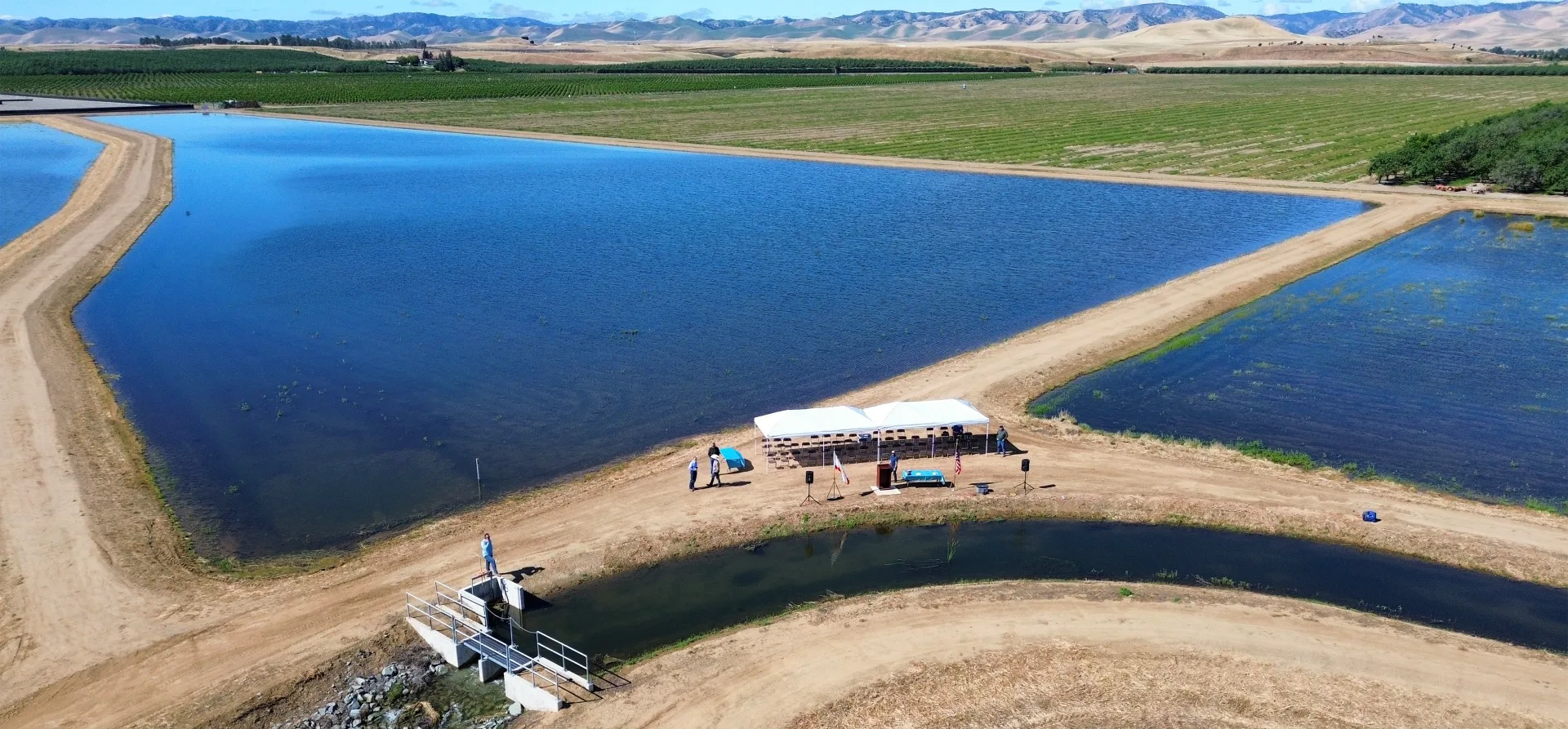 Drone photo of large ponds between raised dirt paths, one containing two event tents at the Orestimba Recharge and Recovery project