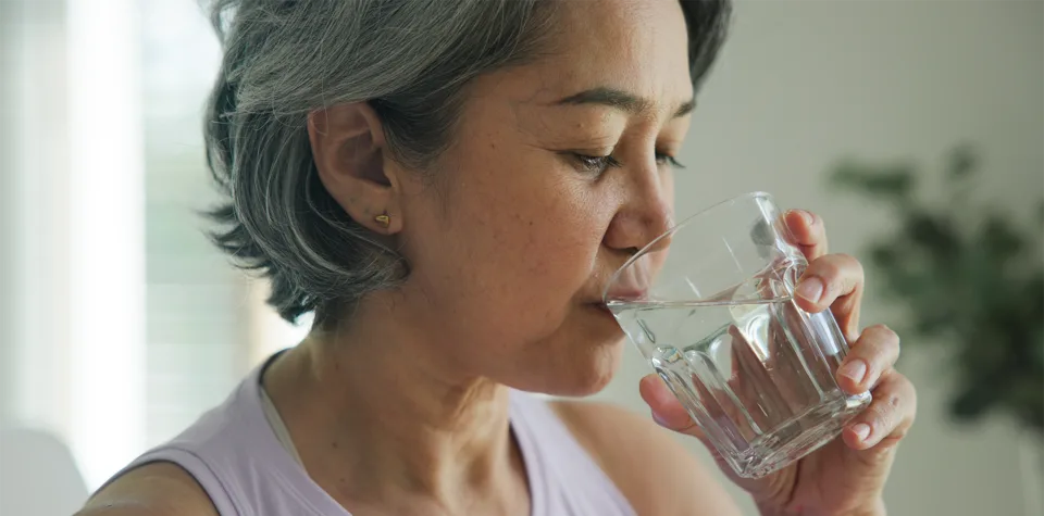 A person drinking a glass of drinking water. Credit: Adobe Stock