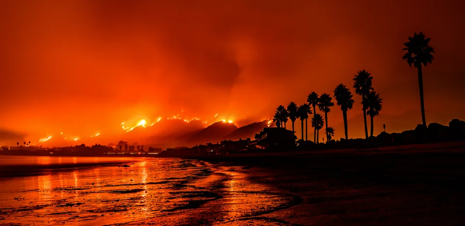 Photo showing a Montecito, CA beach at night with the Thomas Fire burning a hillside in the background